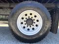 Close-up of a white wheel with a central hub and multiple bolt holes mounted on a heavy-duty tire labeled Super Traction