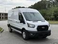 A white 2022 Ford Transit cargo van with a sleek design and distinctive front grille parked in a lot