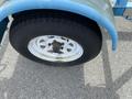 A close-up of a tire on a blue U-Built Reel Trailer showing tread detail and a white rim with a central hub