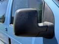 Close-up of the side mirror of a blue 2006 Ford Econoline with water droplets on its surface