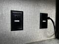 Two black electrical outlets mounted on a textured wall in a recreational vehicle