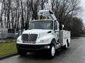 A white 2013 International DuraStar utility truck with a bucket lift and tool compartments on the sides