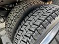 Close-up of two large, heavily treaded tires mounted on a 2011 Ford F-450 SD showing wear and texture detail