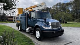 A blue 2009 International 4300 bucket truck with a rear utility box and an extended aerial lift arm mounted on the top