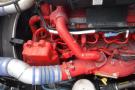 A 2015 Kenworth T660 engine with vibrant red hoses and components prominently displayed against a backdrop of mechanical parts