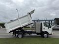 A 2014 Hino 195 dump truck with its bed raised for unloading displaying a white chassis with a silver side compartment