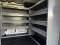 The interior of a 2017 Ford Transit van featuring multiple metal shelving units arranged in organized rows for storage