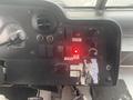 The dashboard of a 2012 Ford Econoline featuring controls for seatbelt, door, and various switches along with a red indicator light illuminated