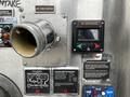 A metal outlet pipe with a round opening labeled as "#2 DISCHARGE" next to a digital control panel with buttons and display, part of a 2009 Spartan Gladiator vehicle