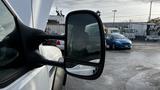 A close-up view of the side mirror of a 2007 Ford F-550 truck with a visible reflection of a blue car in the background