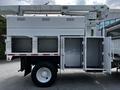 A white 2012 Freightliner M2 106 utility truck with an elevated bucket and multiple storage compartments on the side