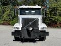 A 2005 Volvo VND 122 heavy-duty truck with a white exterior and prominent grille features, equipped with a front-mounted attachment and multiple roof lights