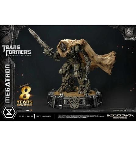 A detailed statue of Megatron from Transformers: Dark of the Moon, featuring a robotic figure in a cloak holding a weapon, standing on a base with Transformers branding