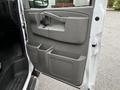 A 2023 GMC Savana vehicle door interior featuring a gray plastic panel with a handle cup holder and storage compartments