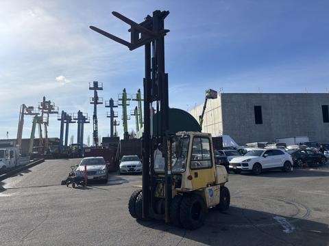 A yellow 1993 Hyster H80XL forklift with a tall mast and extended forks is parked in a busy loading area