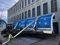 A blue snowplow with white snowflake designs is secured to a trailer with straps showcasing its curved blade and metal frame