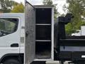 A 2015 Mitsubishi Fuso FE with an open cargo area featuring shelves on one side and a section for loading on the other
