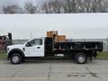 A 2021 Ford F600 white pickup truck with a black flatbed loaded with wooden crates on the back