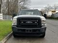 A 2014 Ford F-250 SD in the foreground with a black grille and Ford emblem prominently displayed on the front