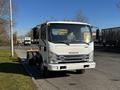 A white 2017 Isuzu NQR truck with a flatbed and orange lights on top parked on the side of a road