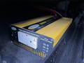 A two-tone yellow and black power inverter with a standard outlet and indicators for load and power levels