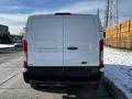 A white 2018 Ford Transit van is parked with its rear facing the viewer showcasing its large cargo area and signature tail lights