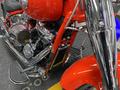 A close-up of a 2024 Harley Davidson Fat Boy showcasing its chrome engine components and a vivid red frame