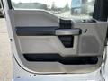 A close-up of the interior door panel of a 2018 Ford F-550 featuring a gray and black color scheme with a door handle speaker grille and control buttons