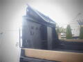 A black dump bed attached to a 2008 Ford F-550 with wooden planks in the cargo area and a metal hydraulic lift mechanism