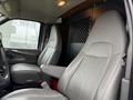 Interior of a 2014 GMC Savana showing two gray leather front seats with armrests and a partition behind them