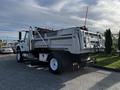 A 2011 International 7500 dump truck with a silver body and a tilting bed is positioned with the back facing the viewer and a red safety pole protruding from the bed