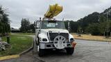 A 2006 International 7500 truck equipped with a yellow aerial lift at the front and a distinctive white and orange design on the body