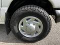 A close-up of a wheel from a 2004 Ford Econoline featuring a silver rim and rugged tire tread design
