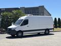 A 2019 Mercedes-Benz Sprinter van with a white exterior and black accents parked on a surface showcasing its distinct shape and design