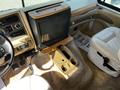 Interior view of a 2000 Ford Motorhome featuring a driver’s seat a passenger seat a central console with cup holders and a wooden TV stand with a television set
