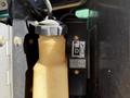 A close-up view of a yellow hydraulic fluid reservoir with a black cap and a gauge indicating fluid level next to a fuel indicator on a machine