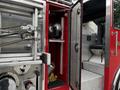 A red 1991 Sutphen Deluge fire truck with metallic details and a partially open door revealing equipment inside