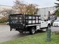 A 2019 Ford F-350 SD flatbed truck with a black metal rack and toolbox parked on a grassy area