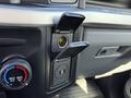 A dashboard of a 2024 Ford F-550 showing climate control knobs and a power outlet with a protective cover open