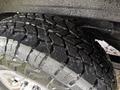Close-up of a rugged tire with deep treads designed for traction showcasing a shiny rim and water droplets on the surface