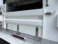 A white storage compartment door on the side of a 2016 Ford F-550 with metal hinges and a latch system