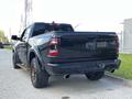 A black 2019 RAM 1500 truck viewed from the rear with distinctive taillights and a sporty design featuring oversized tires and a dual exhaust system