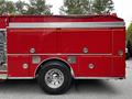 A side view of a red 1991 Sutphen Deluge fire truck showing its large wheels shiny chrome accents and compartments