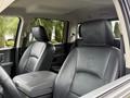 Interior of a 2018 RAM 1500 featuring two black leather front seats with RAM logo on the headrests and a central armrest storage compartment
