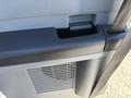 A close-up view of a 2016 Ford F-550's interior armrest with a cup holder and textured surface