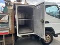 A 2008 Mitsubishi Fuso FE180 with an open side compartment displaying its empty metal interior and shelves