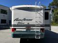 A 2000 Ford Pace Arrow Vision motorhome with a white exterior and teal accents featuring a ladder on the back