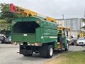 A green 2015 Freightliner M2 106 truck with a yellow aerial lift extending from the rear and a large storage compartment in the back