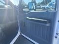 A 2014 Ford F-250 SD door interior featuring a black handle and panel with storage compartments and a side mirror visible
