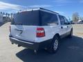 A 2013 Ford Expedition in white with a black rear and tinted windows parked at an open area showing its back and side profiles
